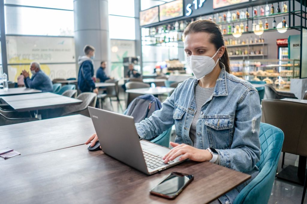 pexels photo 12945016 12945016 A woman wearing a face mask works on her laptop at a café amidst a pandemic.