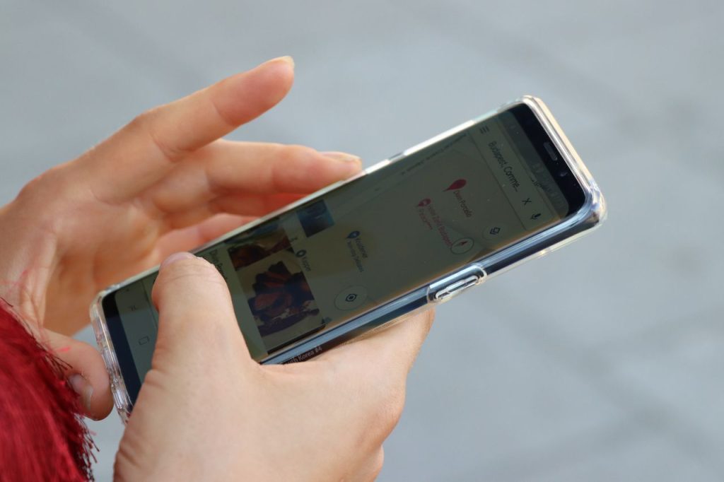 pexels photo 1298473 1298473 Hands holding a smartphone with a clear case, browsing a map outdoors.