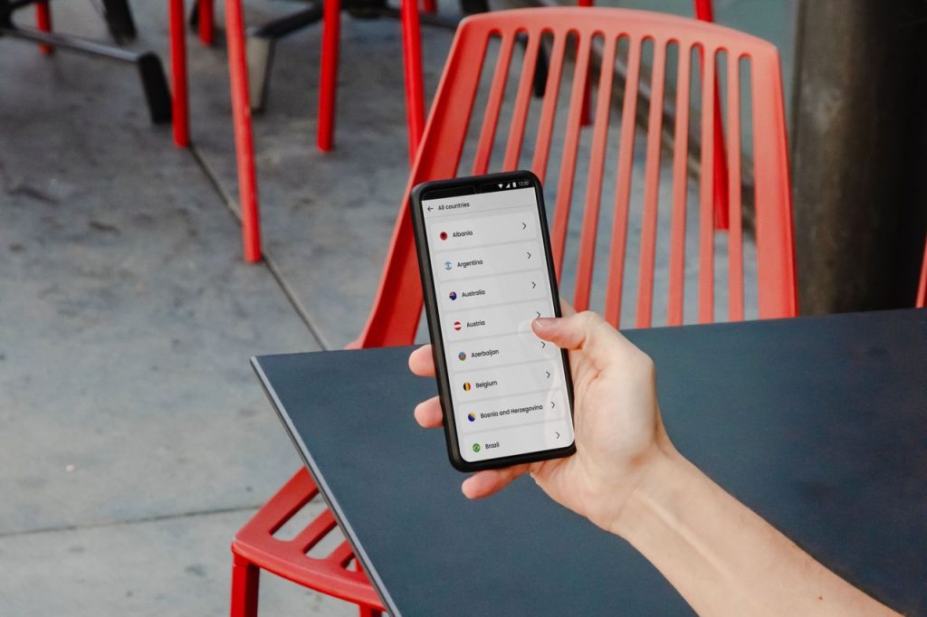 pexels photo 20791610 20791610 A person holding a smartphone showing country options at an outdoor café in New York City.